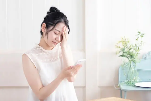 スマホを使いすぎて、頭痛が起きている女性