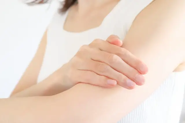 腕をマッサージする女性