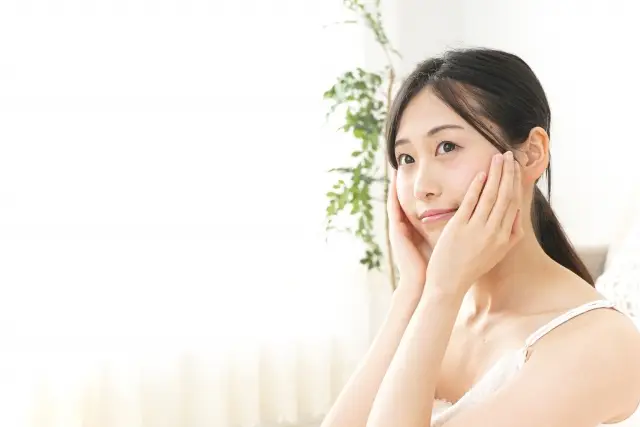フェイスラインに手をあてて、小顔ケアをする女性